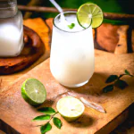 Limonada de coco em um copo alto com canudo, decorado com uma fatia de limão e folhas de hortelã