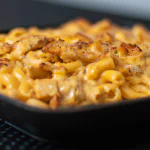 Macarrão com frango e queijo servido em um prato branco.