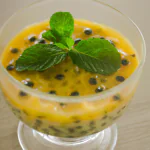 Mousse de maracujá em uma tigela de vidro, decorada com sementes de maracujá e hortelã.