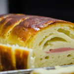 Pão recheado recém-assado sobre uma tábua de madeira.