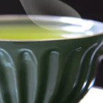 Uma xícara de chá verde fumegante em uma mesa de madeira.