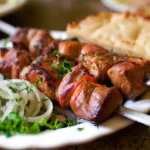 Molho-de-carne grelhado shashlyk servido com pão de trigo e molhos.