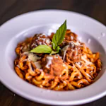 Macarrão bolonhesa com almôndegas servido em um prato branco.