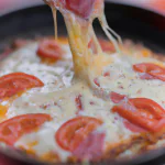Pizza de liquidificador com cobertura de queijo e tomate