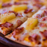 Pizza Hawaii com abacaxi, presunto e bacon em um prato branco